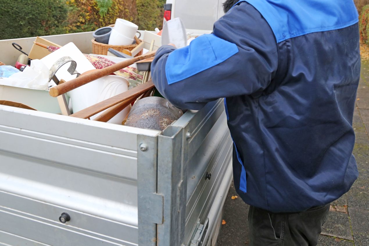 Mitarbeiter eines Entrümpelungsdienstes in Hamburg beim Beladen eines Anhängers mit Sperrmüll und Haushaltsgegenständen